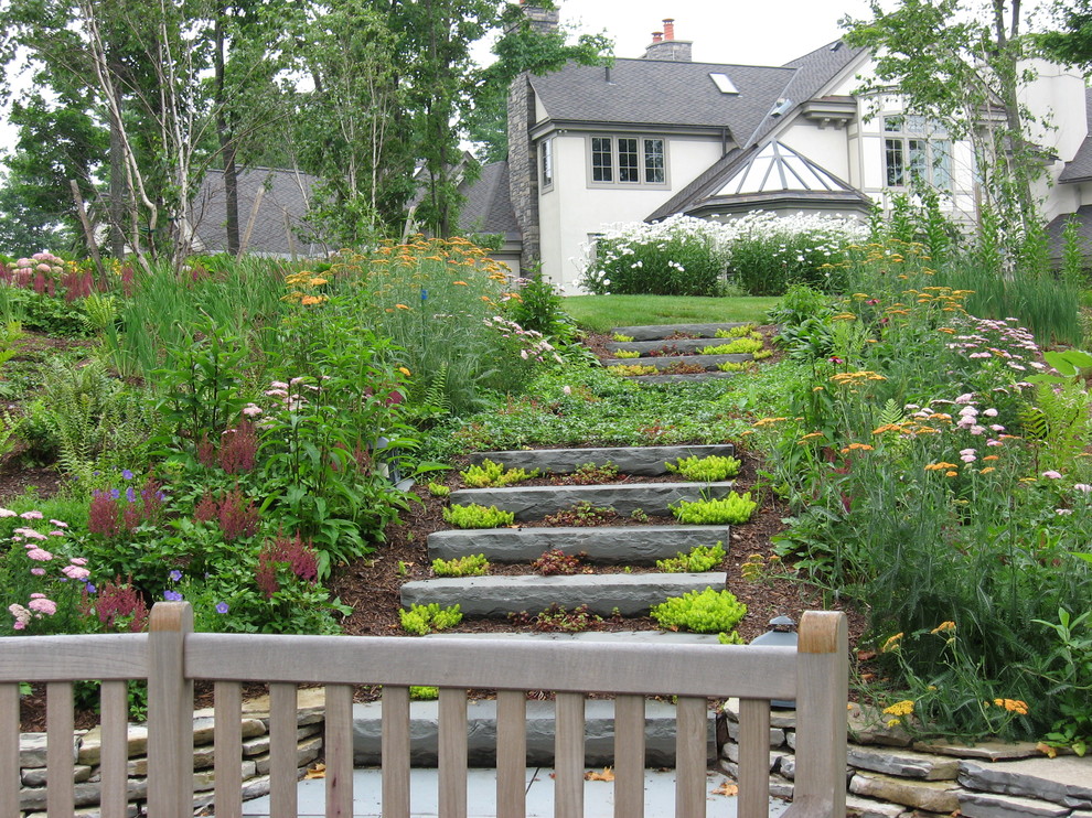 Cette image montre un jardin traditionnel l'été avec une pente, une colline ou un talus et des pavés en pierre naturelle.