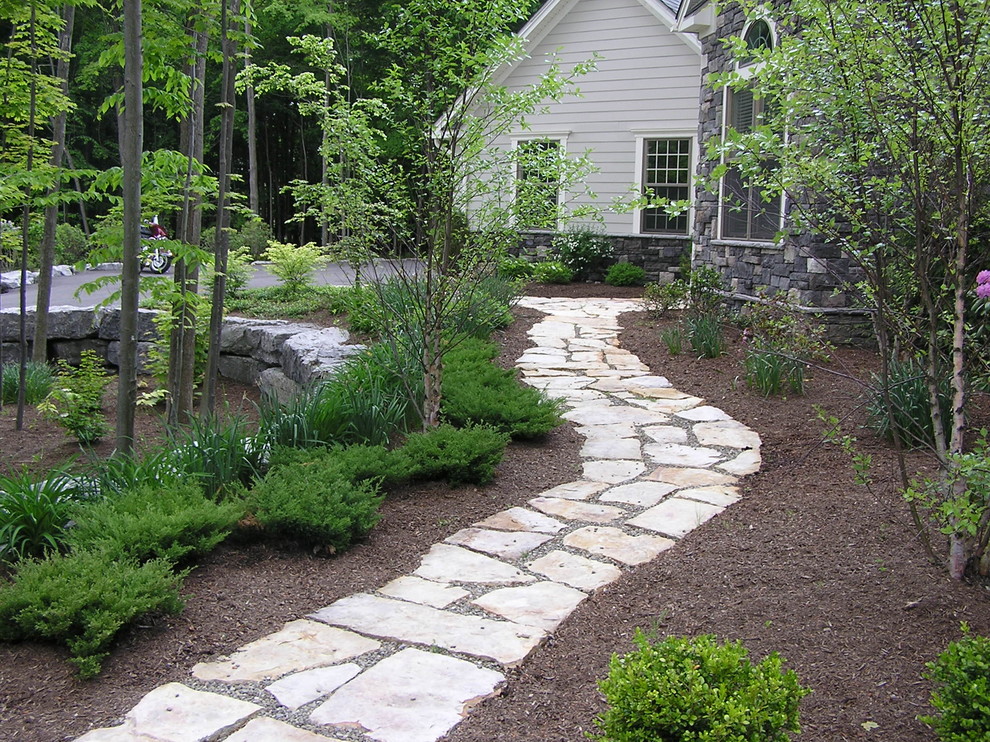 Idee per un giardino tradizionale davanti casa con un muro di contenimento e pavimentazioni in pietra naturale