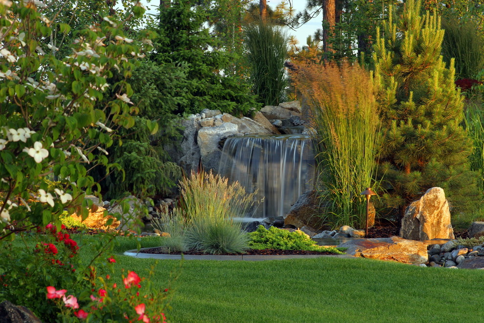 Foto på en stor funkis trädgård, med en fontän och naturstensplattor