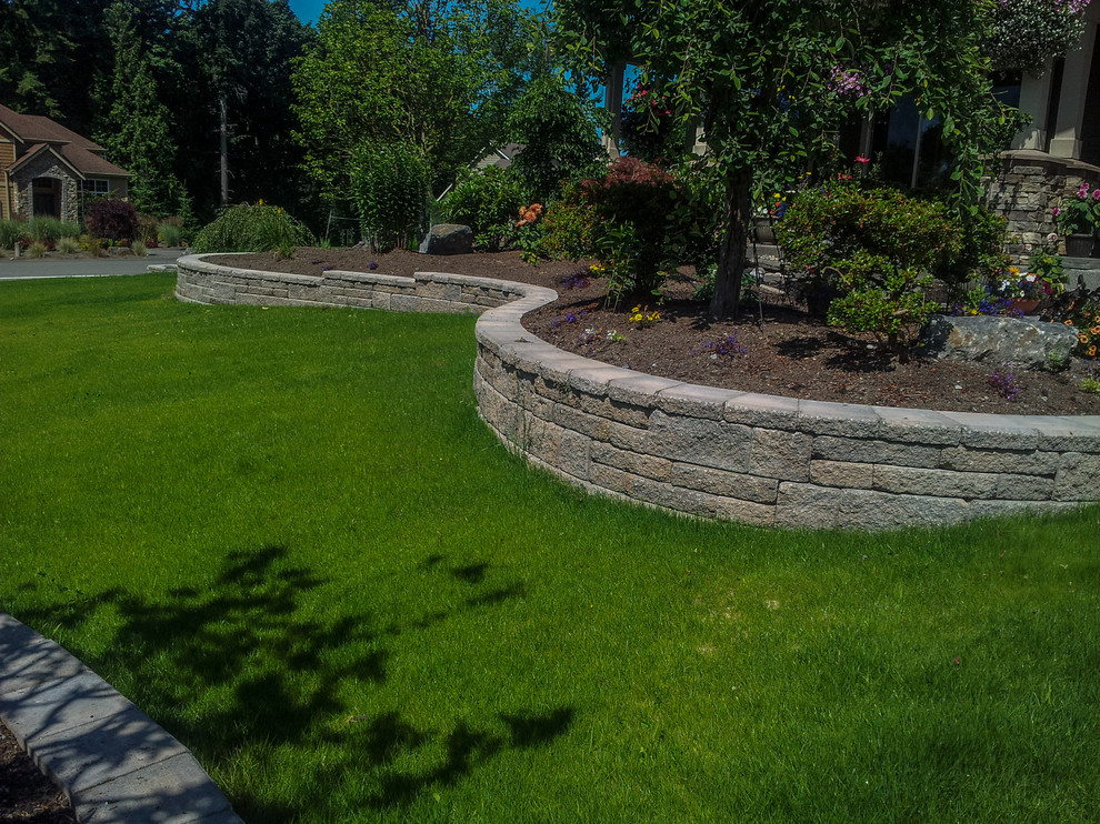 Aménagement d'un jardin arrière classique de taille moyenne et au printemps avec un mur de soutènement, une exposition partiellement ombragée et des pavés en pierre naturelle.