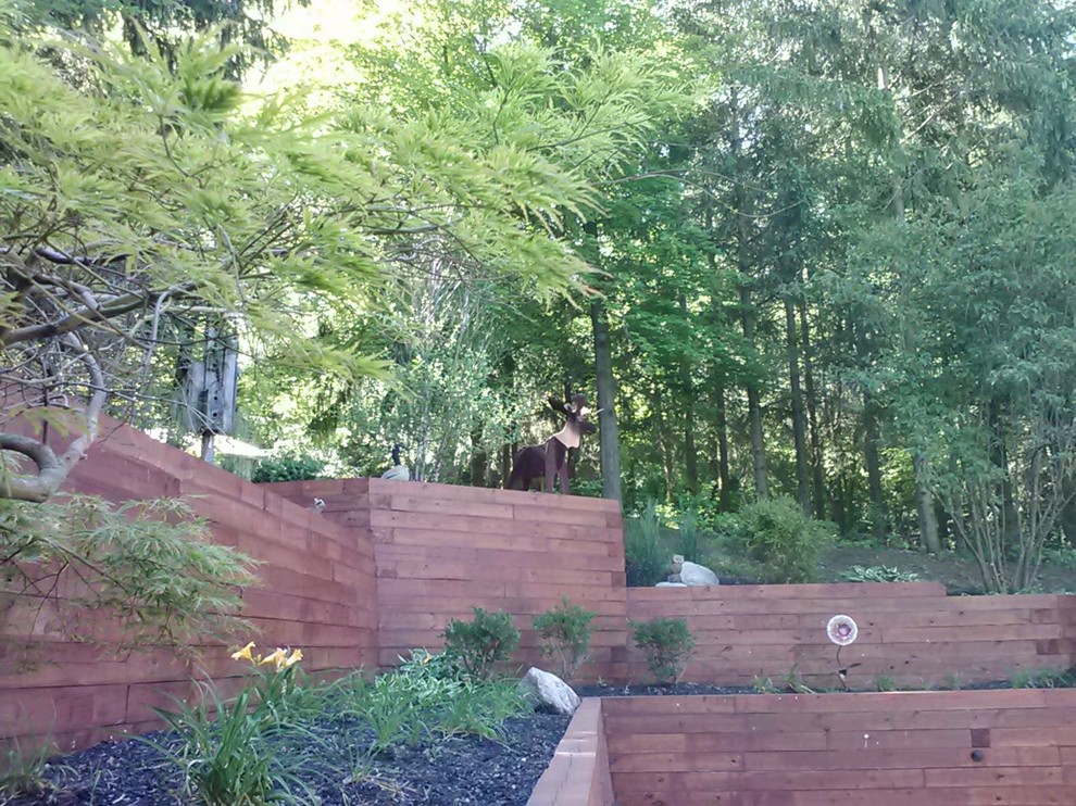 Cette image montre un grand jardin chalet l'été avec un mur de soutènement, une exposition ensoleillée, une pente, une colline ou un talus et un paillis.