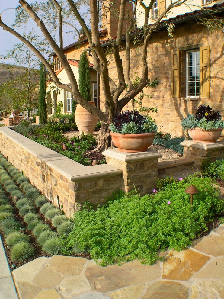 На фото: засухоустойчивый сад среднего размера на переднем дворе в стиле кантри с подпорной стенкой и покрытием из каменной брусчатки с