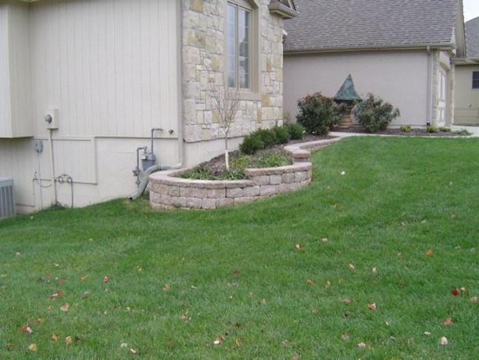 This is an example of a medium sized contemporary side partial sun garden in Other with a retaining wall and concrete paving.