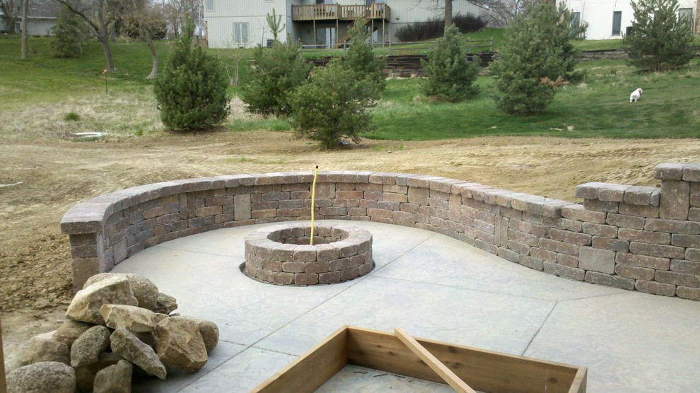 Modelo de jardín tradicional de tamaño medio en patio trasero con muro de contención y adoquines de hormigón