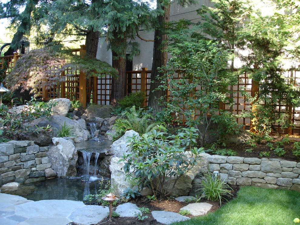Imagen de jardín de estilo zen de tamaño medio en patio trasero con jardín francés, muro de contención, exposición parcial al sol y adoquines de piedra natural