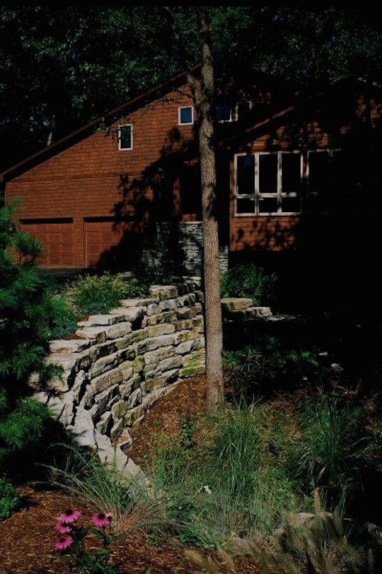 Aménagement d'un grand jardin arrière éclectique avec un mur de soutènement, une exposition partiellement ombragée et des pavés en pierre naturelle.