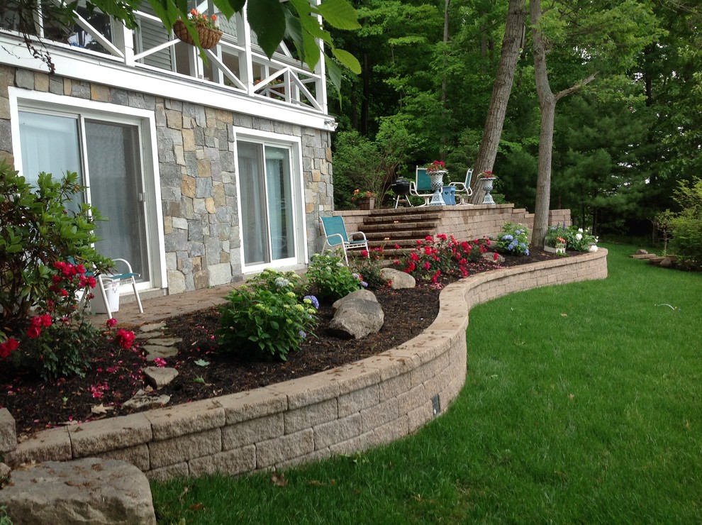 Photo of a medium sized classic back formal partial sun garden for spring in New York with a retaining wall and mulch.