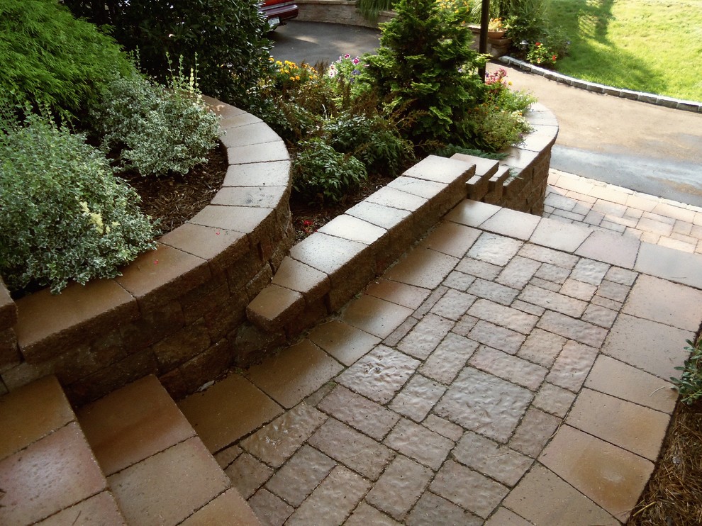 Photo of a large contemporary partial sun front yard brick retaining wall landscape in New York.