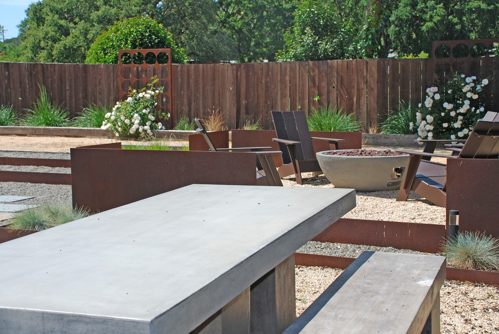 This is an example of a mid-sized contemporary full sun backyard gravel landscaping in San Francisco with a fire pit.