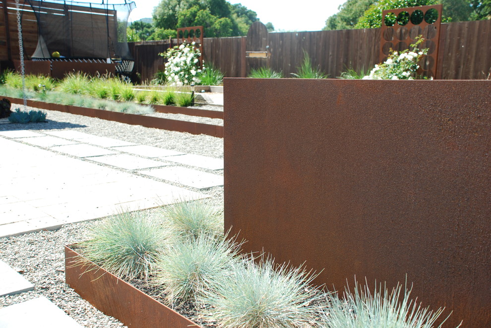 Cette image montre un jardin arrière design de taille moyenne avec un mur de soutènement, une exposition ensoleillée et du gravier.