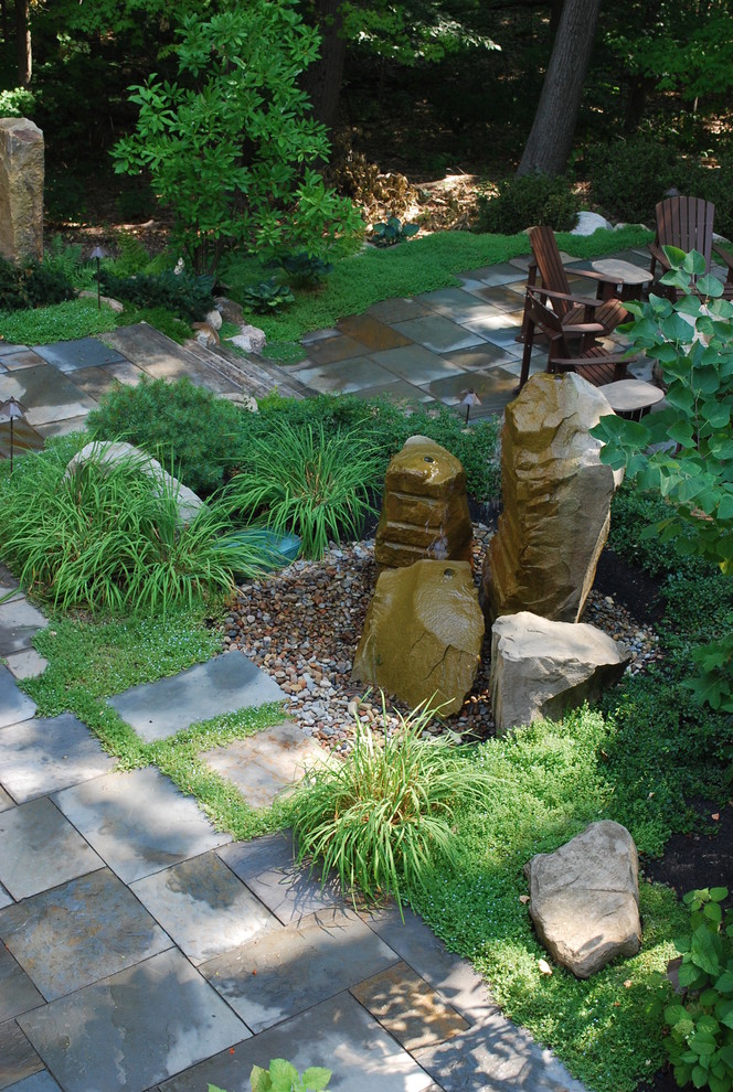 Immagine di un grande giardino classico in ombra dietro casa in primavera con un muro di contenimento e pavimentazioni in pietra naturale