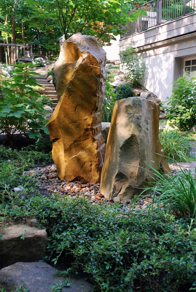 Exemple d'un grand jardin arrière chic au printemps avec un mur de soutènement, une exposition ombragée et des pavés en pierre naturelle.