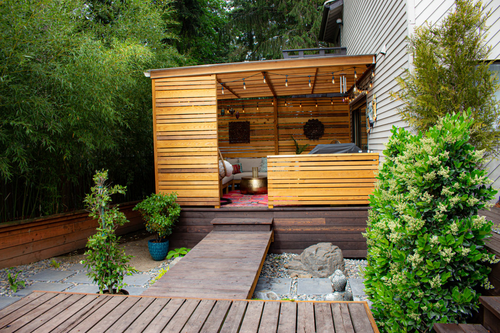 Réalisation d'un petit jardin arrière asiatique l'été avec des solutions pour vis-à-vis, une exposition ombragée et une terrasse en bois.