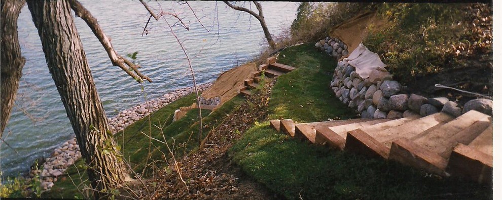 Imagen de jardín clásico grande en patio trasero con muro de contención y adoquines de piedra natural