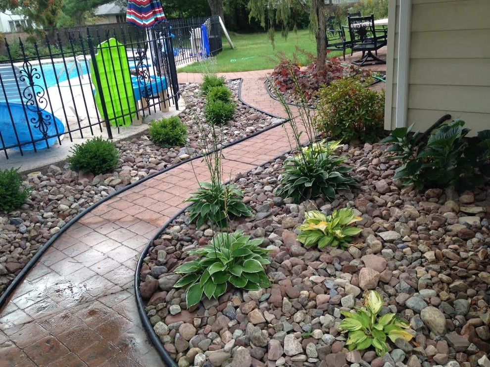Photo of a mid-sized tropical drought-tolerant and partial sun backyard river rock landscaping in New York for spring.