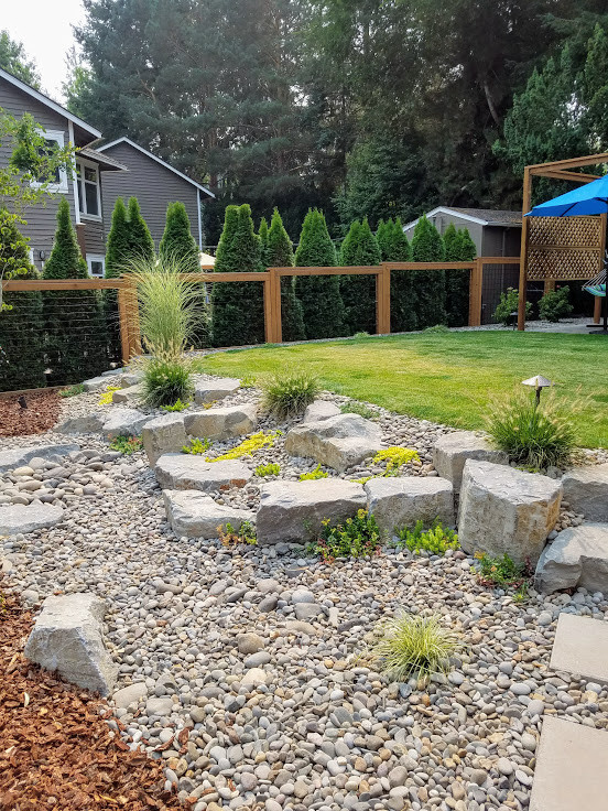 Design ideas for a mid-sized rustic drought-tolerant and full sun backyard stone retaining wall landscape in Portland for winter.