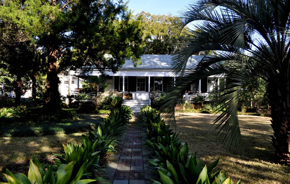 Idéer för stora tropiska trädgårdar framför huset, med marksten i tegel och en trädgårdsgång