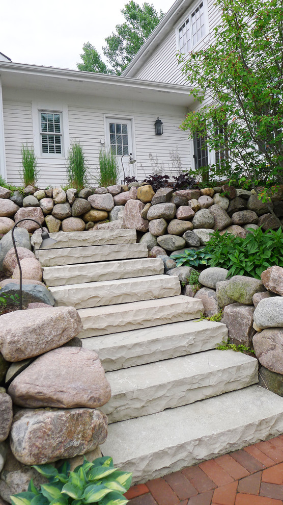 Inspiration for a large farmhouse partial sun hillside stone retaining wall landscape in Chicago for summer.