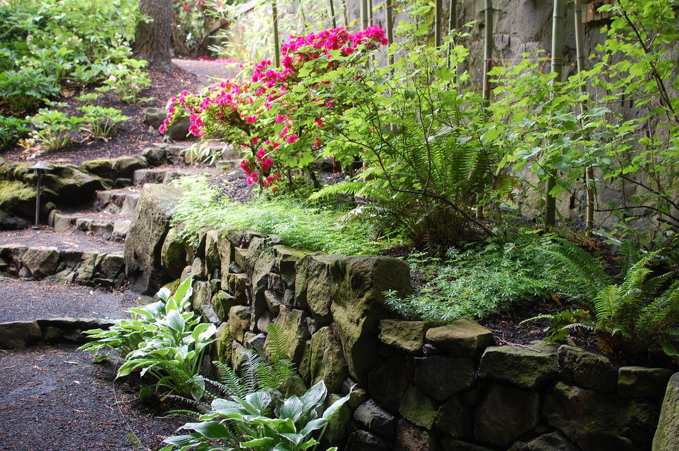 This is an example of a large eclectic partial sun backyard gravel retaining wall landscape in Portland.