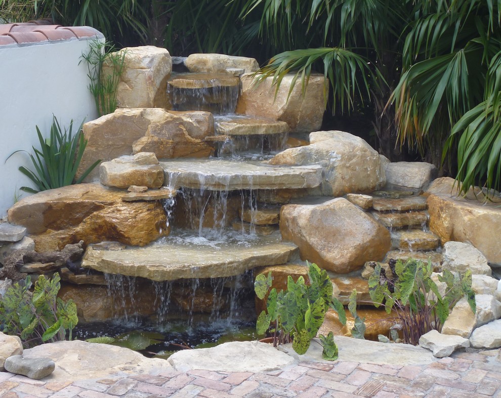 Modelo de jardín clásico grande en patio trasero con fuente y adoquines de piedra natural