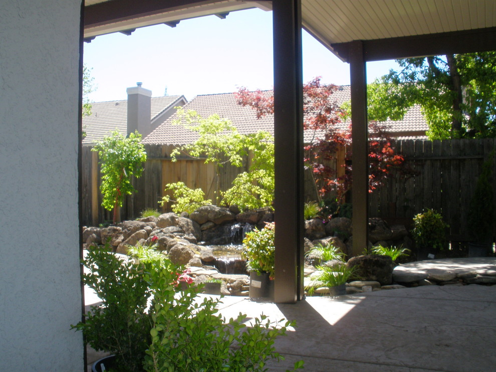 Idee per un grande giardino formale american style esposto a mezz'ombra dietro casa con fontane e pavimentazioni in cemento