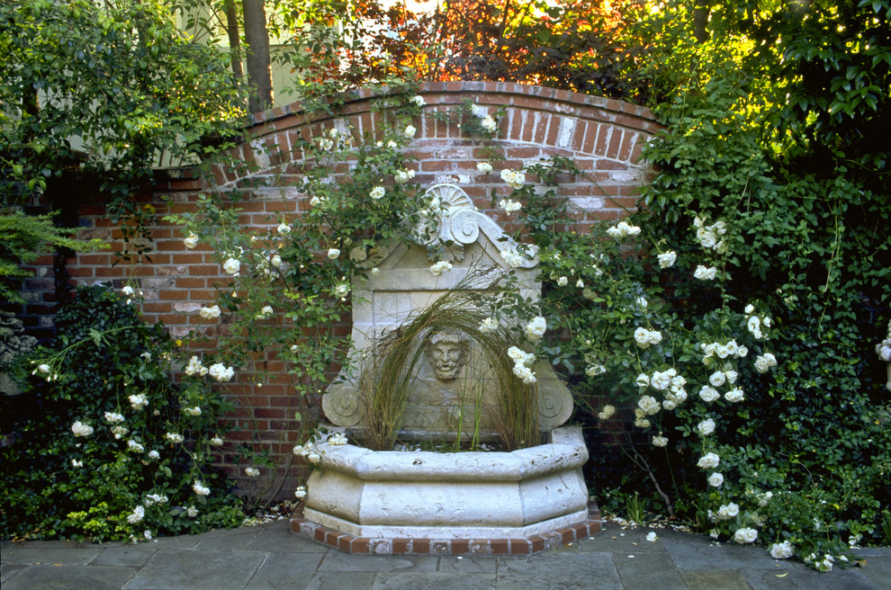 Foto di un giardino formale tradizionale esposto in pieno sole in cortile con fontane