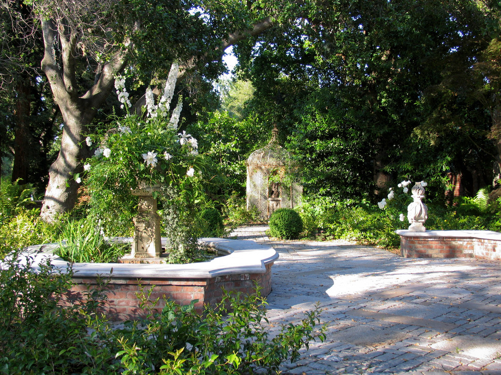 Imagen de jardín clásico de tamaño medio en patio con jardín francés, fuente y adoquines de piedra natural