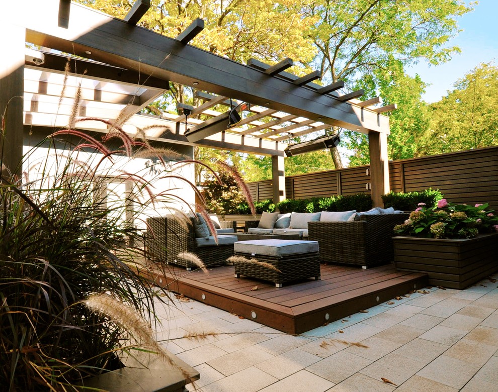 This is an example of a small modern back full sun garden in Toronto with decking and a fire feature.