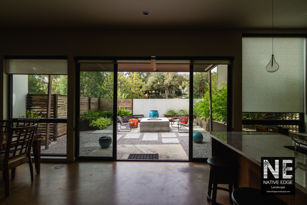 Cette image montre un petit jardin minimaliste avec un foyer extérieur et des pavés en béton.