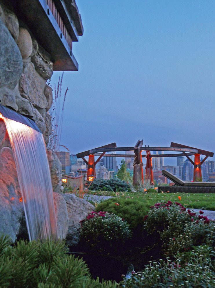 Photo of a craftsman full sun backyard stone water fountain landscape in Calgary for fall.