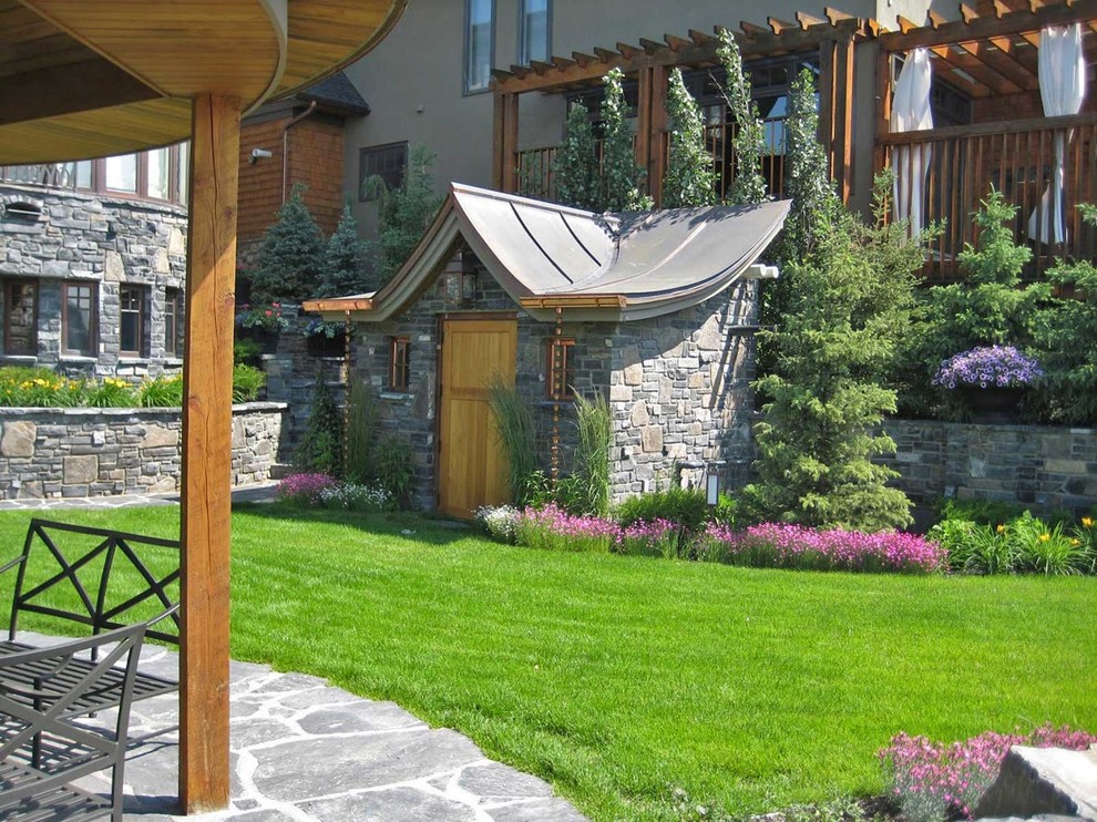 Klassischer Garten hinter dem Haus mit Auffahrt und Natursteinplatten in Calgary