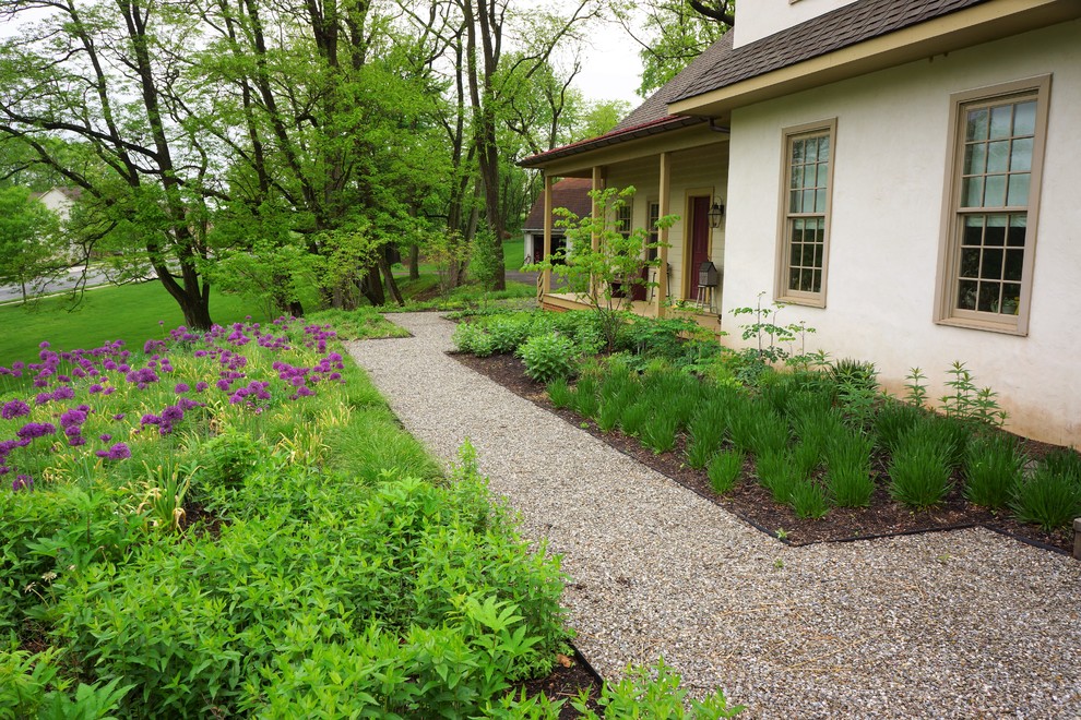 Exemple d'un grand aménagement d'entrée ou allée de jardin au printemps avec une exposition ensoleillée, une pente, une colline ou un talus et du gravier.