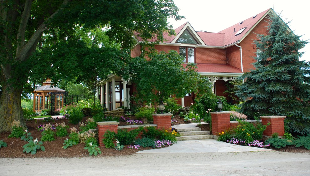 На фото: регулярный сад на переднем дворе в классическом стиле с садовой дорожкой или калиткой и покрытием из каменной брусчатки