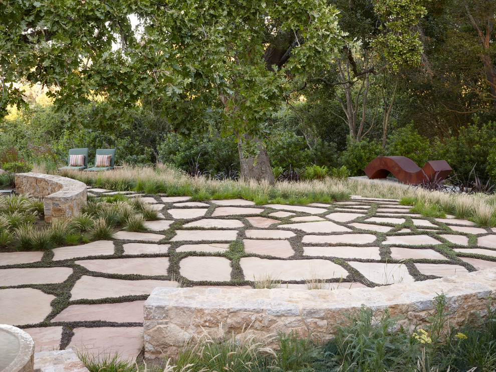 Cette photo montre un jardin arrière chic avec un mur de soutènement et des pavés en pierre naturelle.