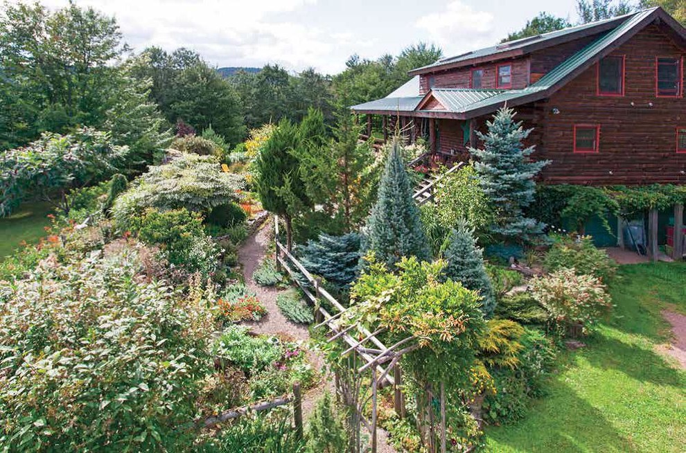 This is an example of a large rustic partial sun backyard gravel landscaping in New York.
