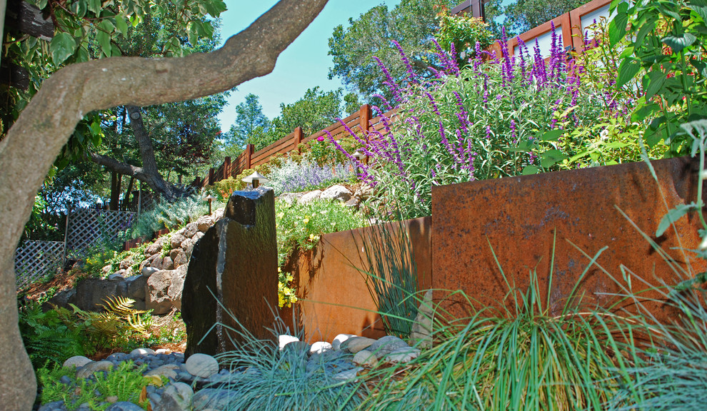 Immagine di un giardino xeriscape contemporaneo esposto a mezz'ombra di medie dimensioni in primavera con un muro di contenimento, un pendio, una collina o una riva e pavimentazioni in pietra naturale