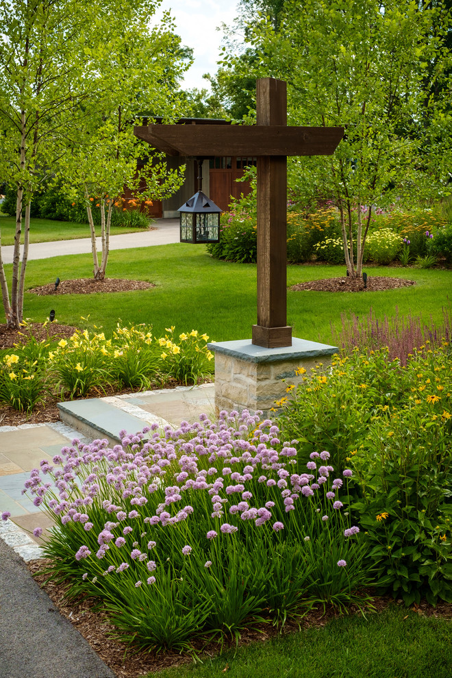 Idée de décoration pour un grand jardin avant tradition avec des pavés en pierre naturelle et un massif de fleurs.