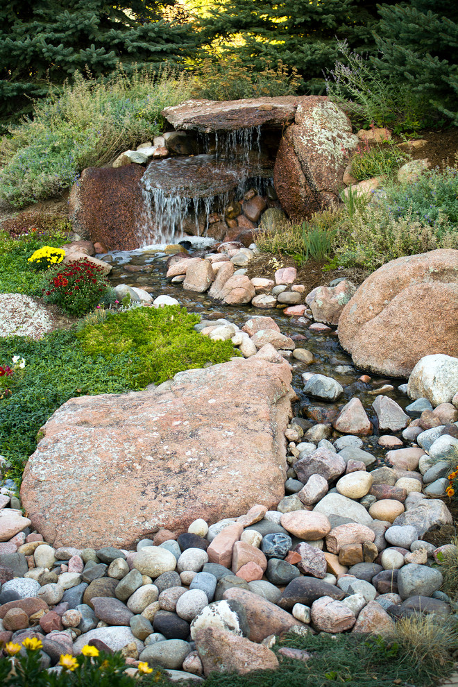 Photo of a mid-sized rustic partial sun backyard gravel water fountain landscape in Denver.