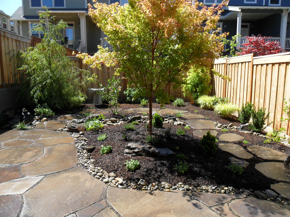 This is an example of a small contemporary back full sun garden in Portland with natural stone paving.