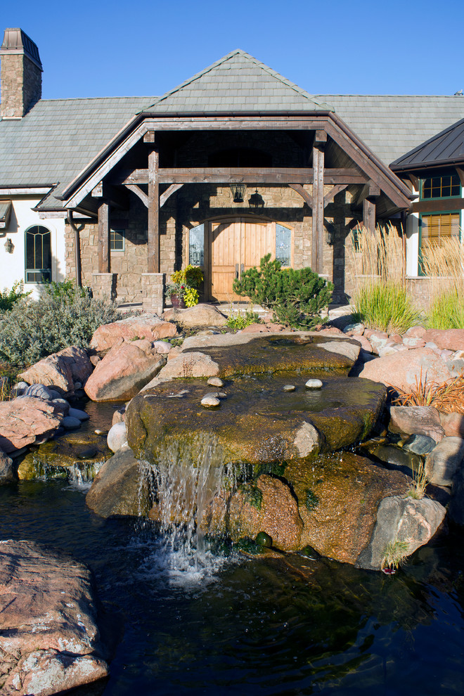 Large rustic front garden in Denver with a water feature and natural stone paving.
