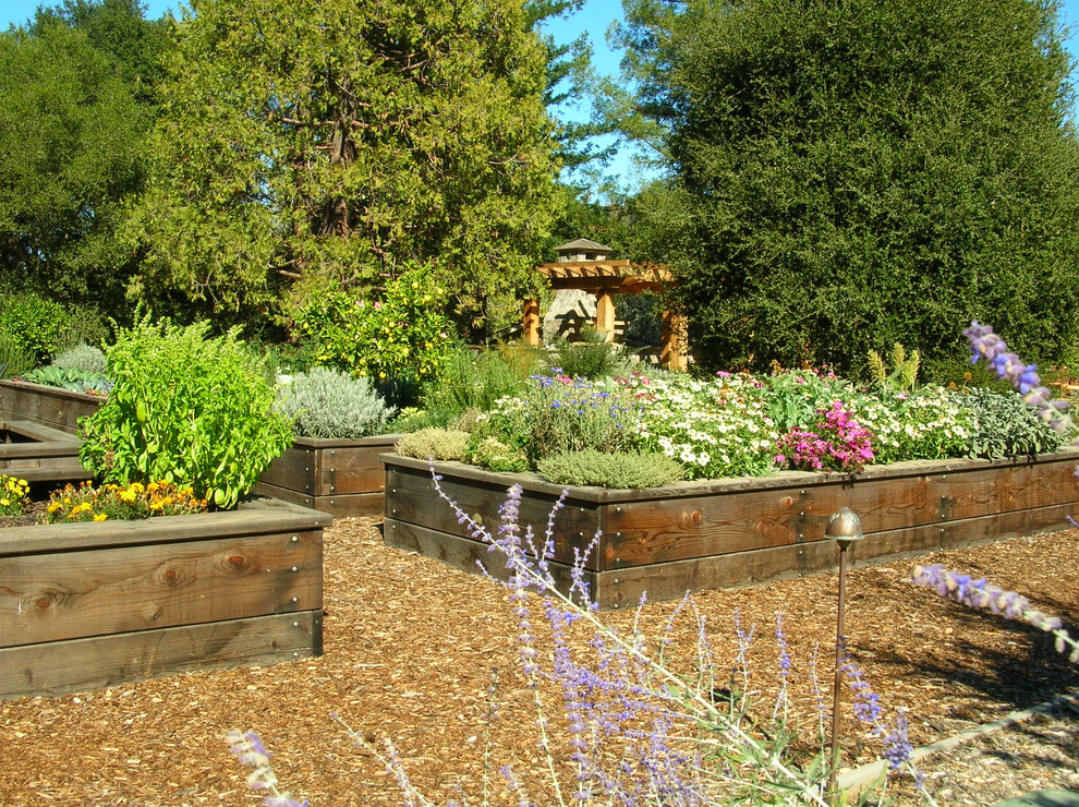 Modelo de jardín de estilo de casa de campo en patio trasero con macetero elevado