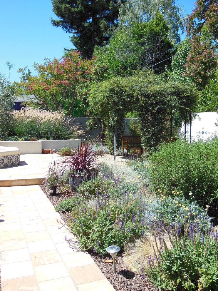 Immagine di un grande giardino formale mediterraneo esposto in pieno sole dietro casa in primavera con fontane e pavimentazioni in pietra naturale