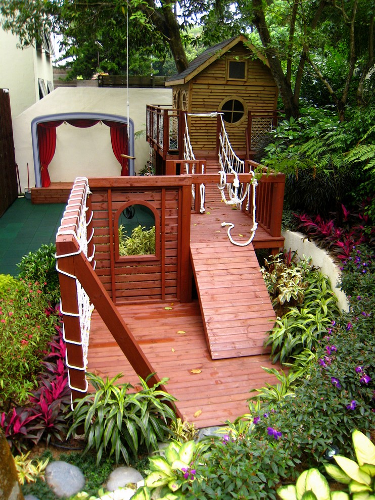 Modelo de jardín tropical grande en primavera en patio trasero con jardín francés, parque infantil, exposición reducida al sol y mantillo