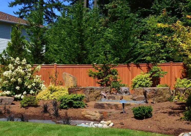 Diseño de jardín ecléctico de tamaño medio en patio trasero con brasero, exposición total al sol y adoquines de piedra natural