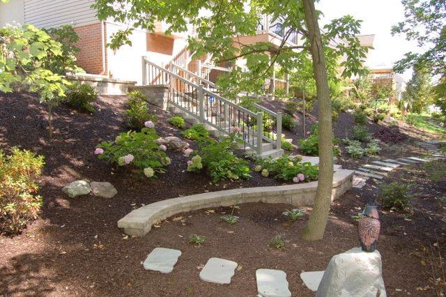 Cette photo montre un jardin tendance de taille moyenne et l'été avec un mur de soutènement, une exposition partiellement ombragée, une pente, une colline ou un talus et des pavés en béton.