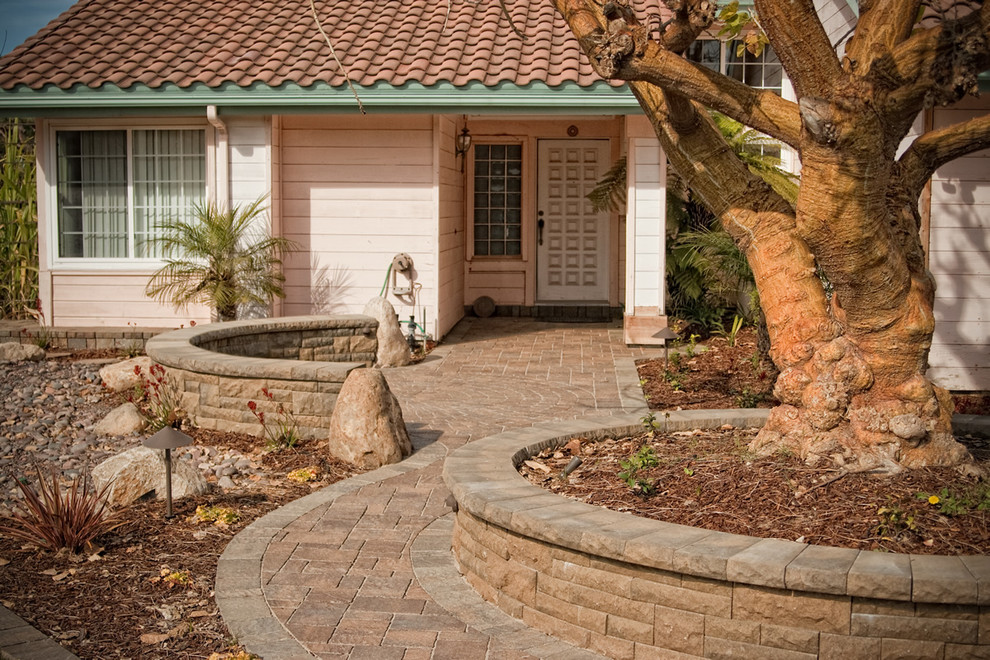 Пример оригинального дизайна: большой участок и сад на заднем дворе с мощением тротуарной плиткой и подпорной стенкой