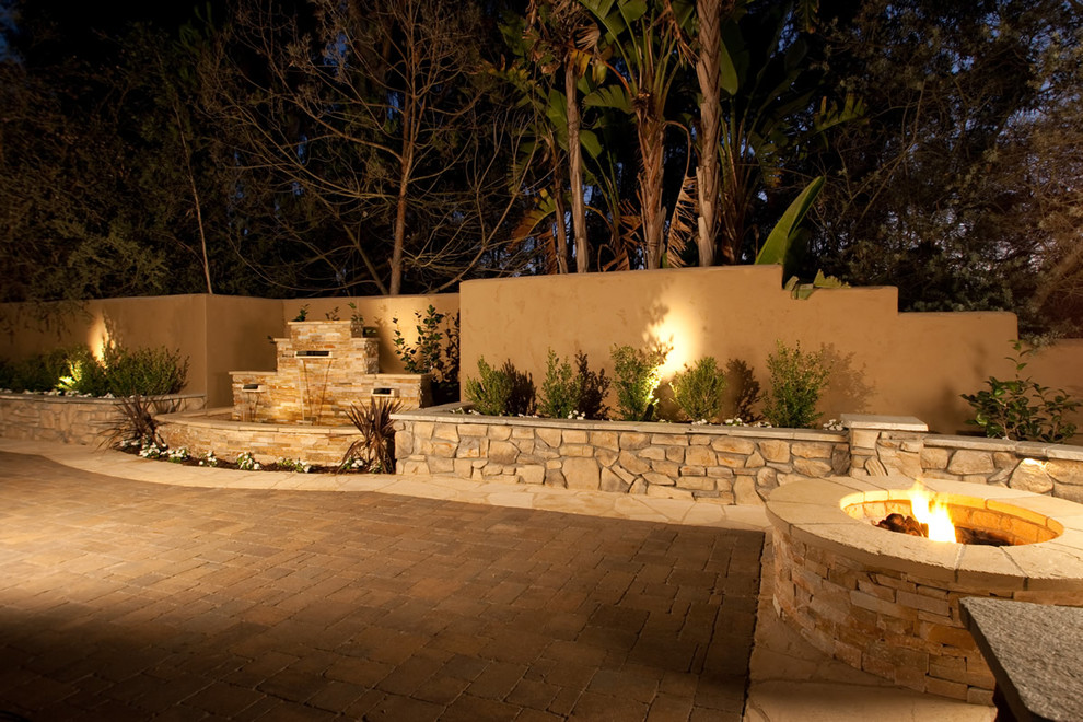 Inspiration for a large backyard concrete paver retaining wall landscape in San Diego.