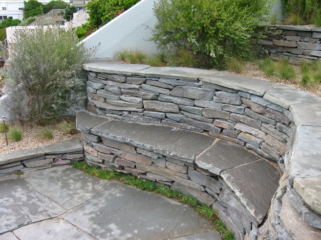 Photo of a medium sized nautical sloped xeriscape full sun garden for winter in San Francisco with a retaining wall and natural stone paving.
