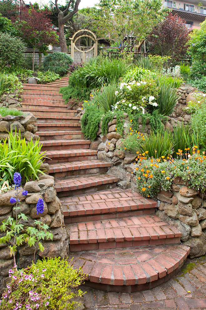 Immagine di un giardino tradizionale con un pendio, una collina o una riva, pavimentazioni in mattoni e scale