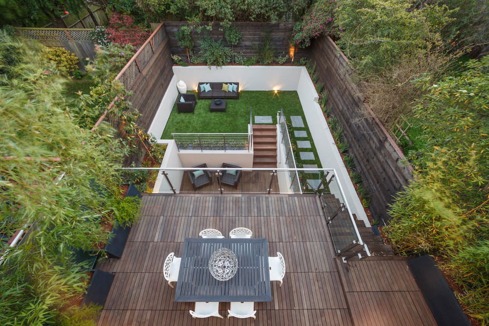 Cette image montre un jardin design de taille moyenne avec une exposition partiellement ombragée et une terrasse en bois.